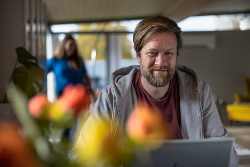 Mann foran pc med dame i bakgrunnen