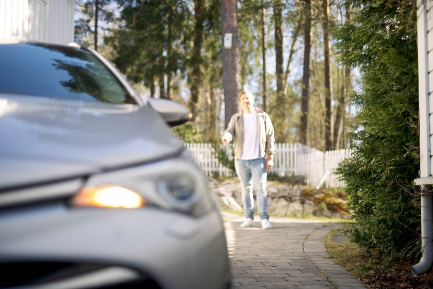 Mann som står i bakgrunnen av en grå bil i skogen