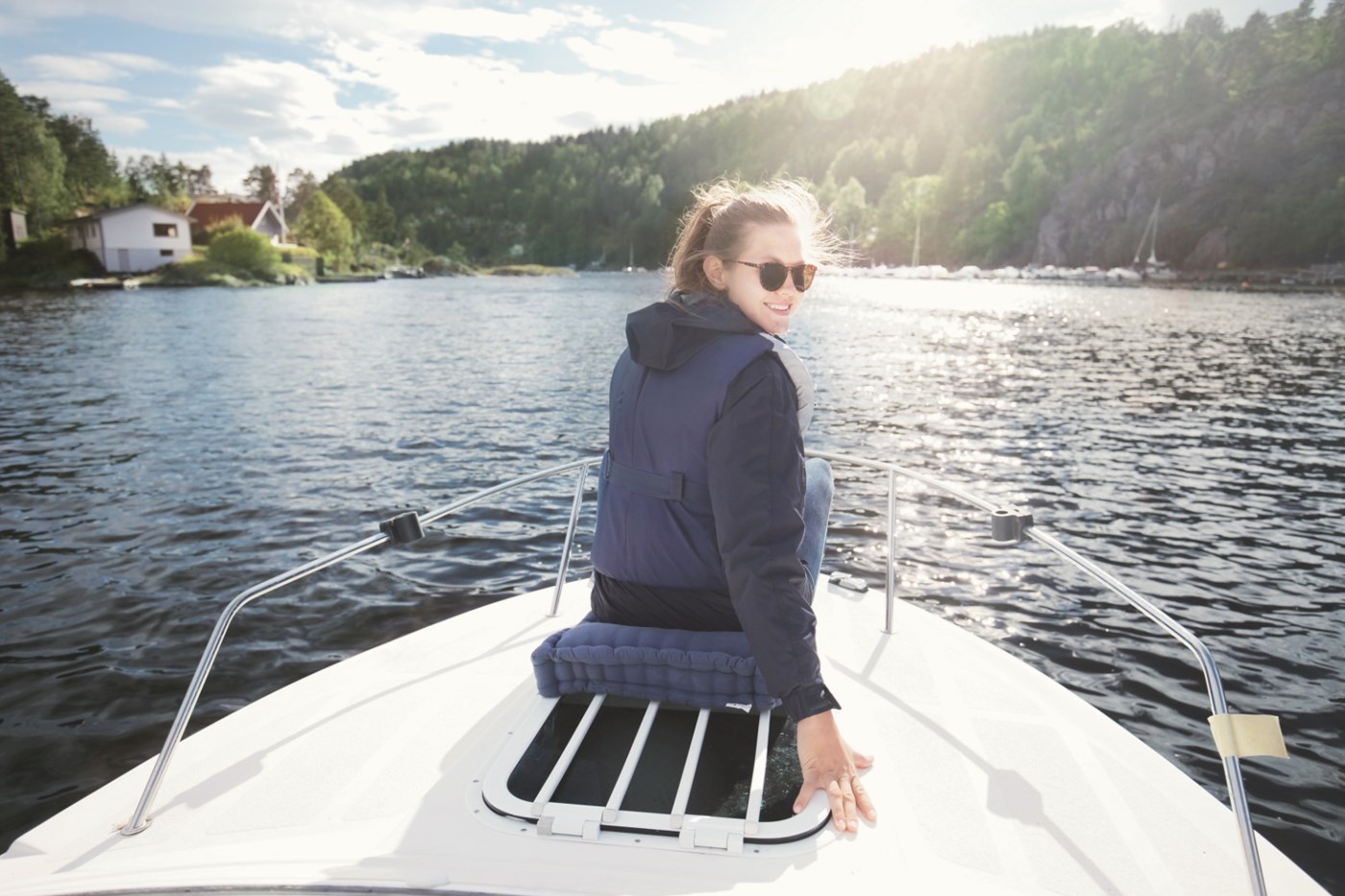 En jente sitter på en båt i nydelig sommervær